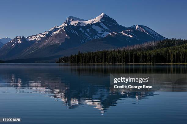 The surrounding snowcapped mountains are reflected in Maligne Lake on June 30, 2013 near Jasper, Alberta, Canada. Jasper is the largest National Park...