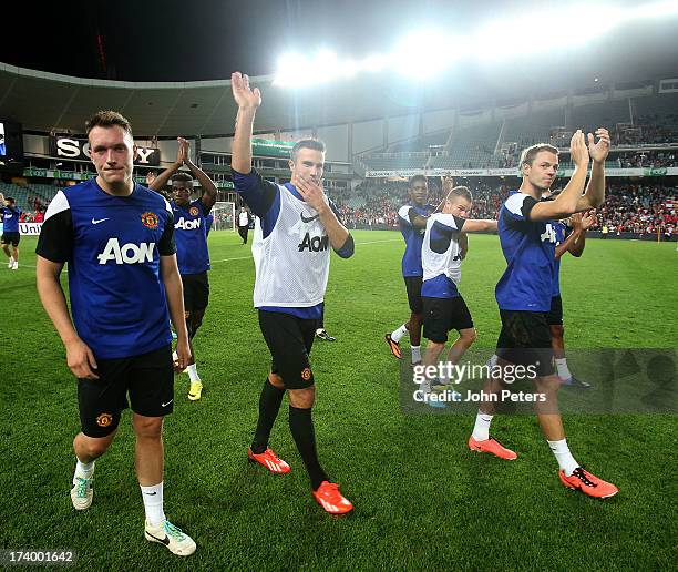 Phil Jones, Robin van Persie and Jonny Evans of Manchester United applaud the fans after a first team training session as part of their pre-season...