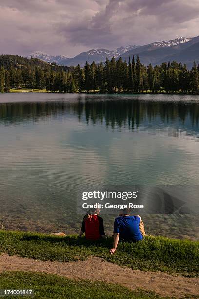 Couple sits at the edge of Beauvert Lake at the Fairmont Jasper Park Lodge on June 24, 2013 near Jasper, Alberta, Canada. Jasper is the largest...