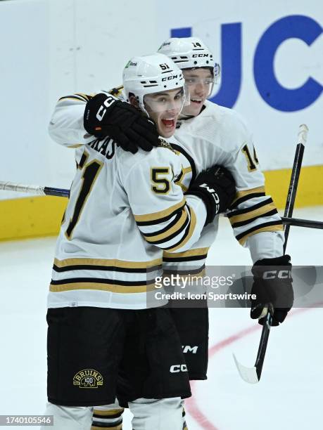 Boston Bruins center Matthew Poitras and defenseman Ian Mitchell celebrate after Poitras scored a goal during the third period of an NHL hockey game...