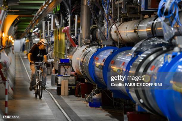 Worker rides on his bicycle in the CERN's Large Hadron Collider tunnel during maintenance works on July 19, 2013 in Meyrin, near Geneva. Tests at the...