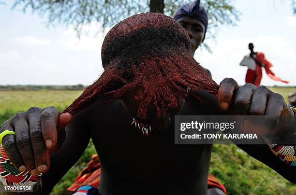Moran warrior from the Samburu tribe disentangles his hair locks in order to clean and re-arrange them on July 16, 2013 in Kisima. Moran, a state...
