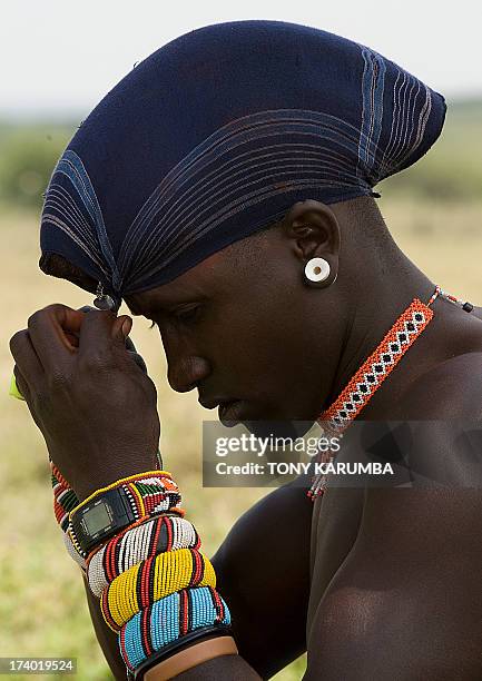 Moran warrior from the Samburu tribe wrappes his dyed hair locks after cleaning them to protect them from rainon July 16, 2013 in Kisima. Moran, a...