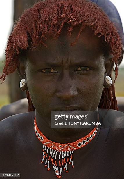 Moran warrior from the Samburu tribe styles his dyed hair locks after cleaning them on July 16, 2013 in Kisima. Moran, a state attained by young boys...