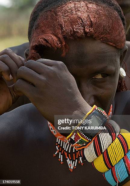 Moran warrior from the Samburu tribe disentangles his hair locks with the help of a peer inorder to clean and re-arrange them on July 16, 2013 in...