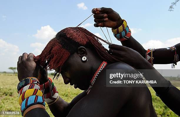 Moran warrior from the Samburu tribe disentangles his hair locks with the help of a peer inorder to clean and re-arrange them on July 16, 2013 in...