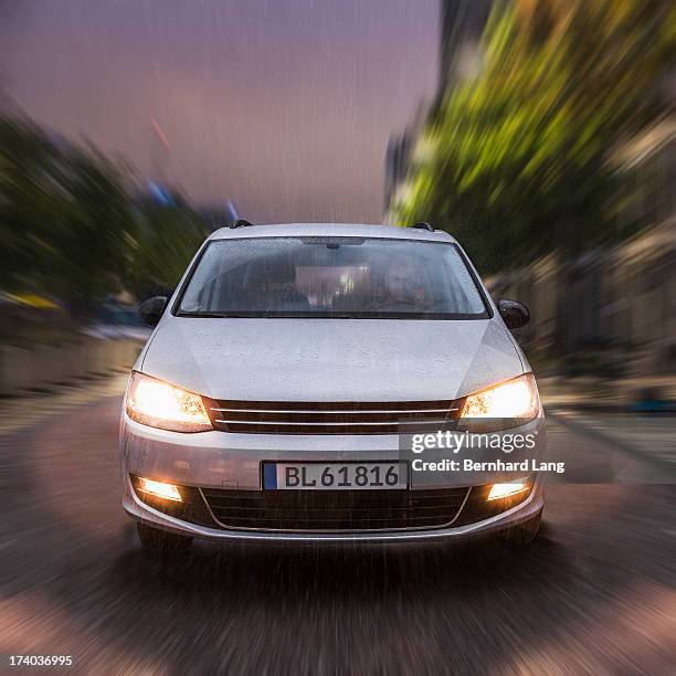 car driving on urban street in the rain - vorderansicht stock-fotos und bilder