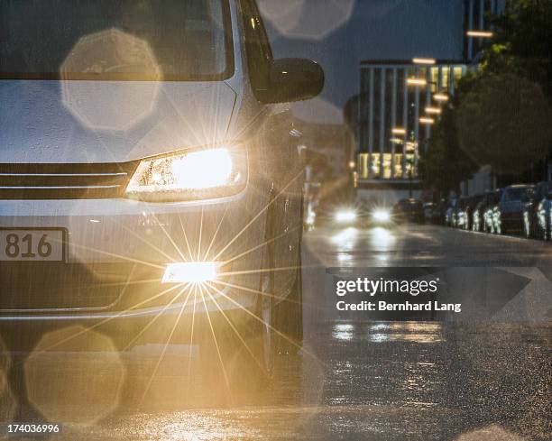 car driving down urban street in rain - headlamp stock pictures, royalty-free photos & images
