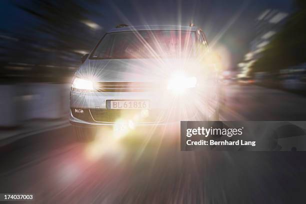 car driving down street, headlights on - farol imagens e fotografias de stock