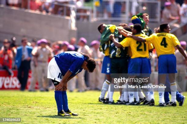 July 1994 World Cup Final 1994, Brazil v Italy - Los Angeles, Roberto Baggio has his hands on his knees in despair as the Brazilian team celebrate...
