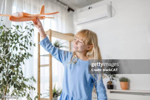 kleines mädchen spielt mit spielzeugflugzeug - toy airplane stock-fotos und bilder