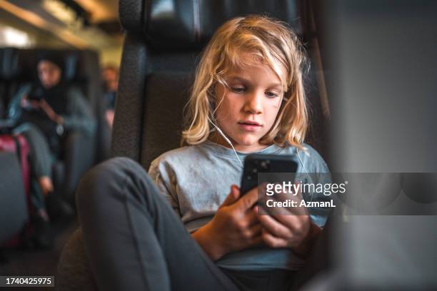 caucasian boy with smartphone and earphones on a train - train denmark stock pictures, royalty-free photos & images