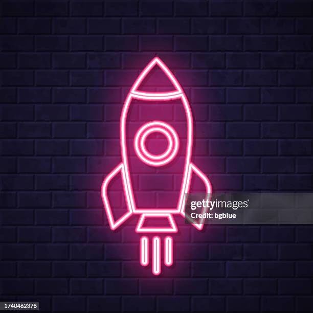 rocket. glowing neon icon on brick wall background - missile launch stock illustrations