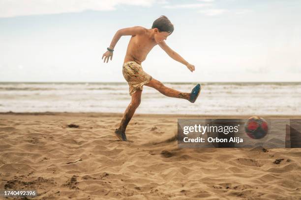 boy playing soccer at the beach - kicking sand stock pictures, royalty-free photos & images