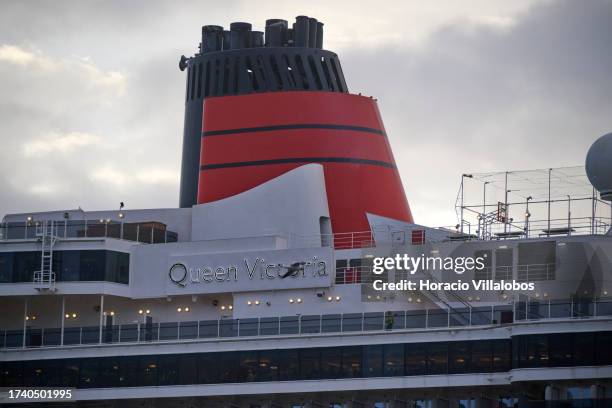 Seagull flies by MS Queen Victoria, a 90,049 GT Vista-class cruise ship operated by the Cunard Line, moored on a stormy morning at Lisbon cruise...