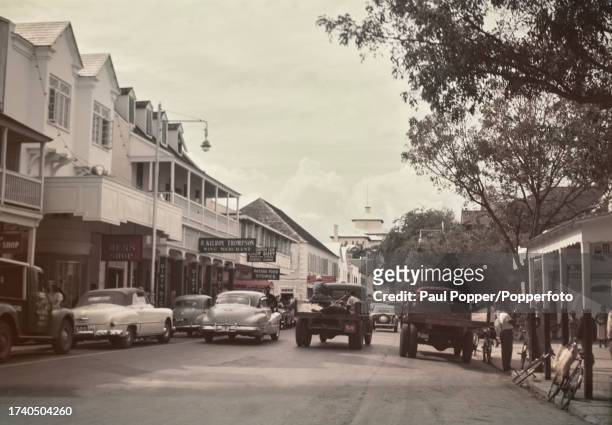 Pedestrians pass cars and trucks on Bay Street in Nassau, The Bahamas, circa 1950. Visible in background is the British Colonial Hotel.
