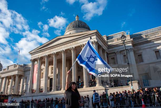 Protester waves an Israeli flag infront of the National Gallery in London. In London's Trafalgar Square, thousands of demonstrators supporting Israel...