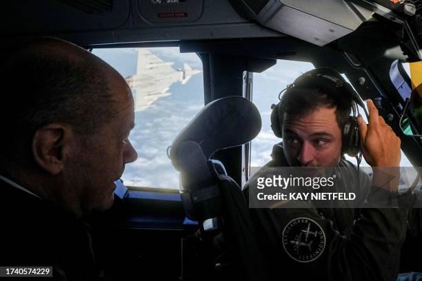 German Chancellor Olaf Scholz talks to the pilot as he sits in the cockpit of an Airbus A400M of the German Air Force on October 23, 2023 in Berlin,...