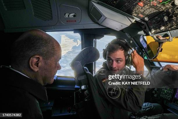 German Chancellor Olaf Scholz talks to the pilot as he sits in the cockpit of an Airbus A400M of the German Air Force on October 23, 2023 in Berlin,...