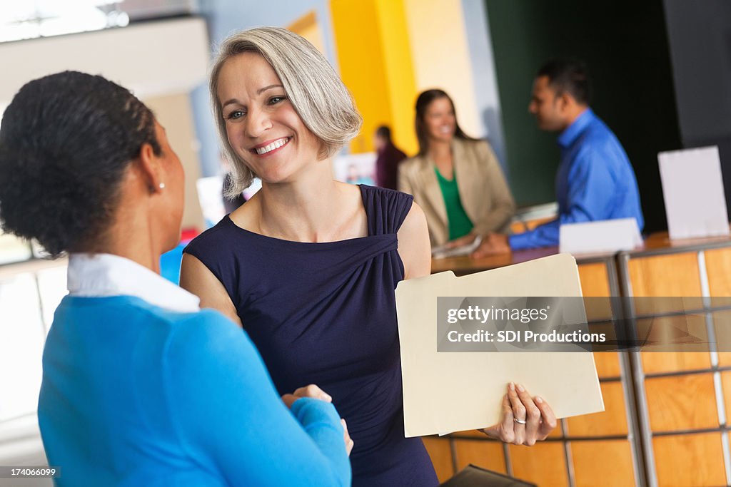 Mature businesswoman shaking hands with prospective employee at job fair