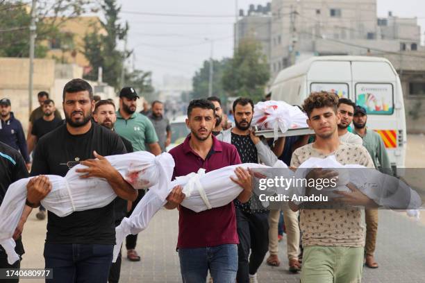 People carry the bodies of the father and 3 children of Palestinian Al Zinaty family killed in the Israeli airstrikes after they were moved from the...