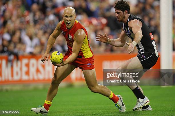 Gary Ablett of the Suns handballs away from Tyson Goldsack of the Magpies during the round 17 AFL match between the Gold Coast Suns and the...