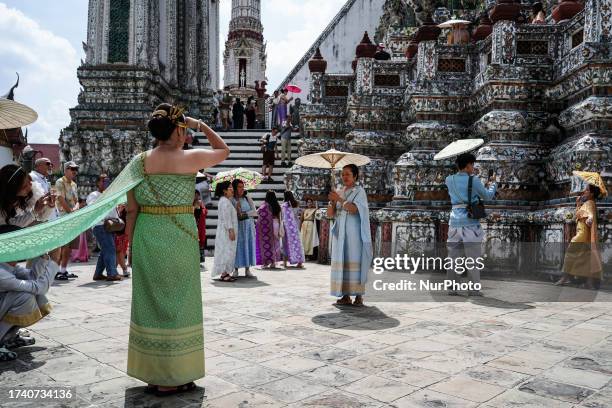 Chinese tourists dressed in Thai traditional costumes rented from a clothing rental shop take memorial photographs during their visit to Wat Arun or...