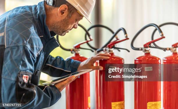 a professional safety inspector inspects fire extinguishers. - fire extinguisher inspection stock pictures, royalty-free photos & images