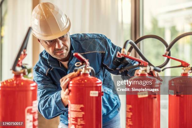 a professional safety inspector checks the fire extinguishers in the hotel restaurant. - fire extinguisher inspection stock pictures, royalty-free photos & images