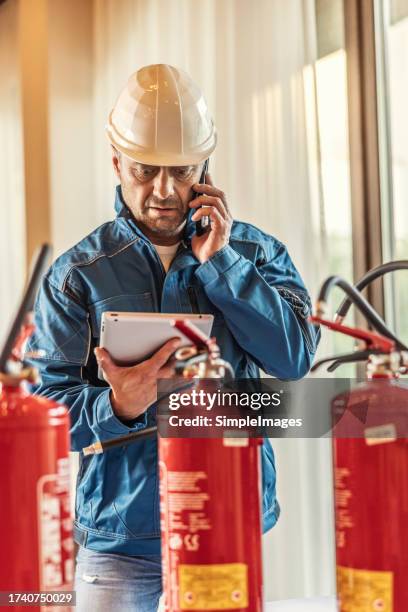 a professional safety inspector checks the fire extinguishers in the hotel restaurant. - fire extinguisher inspection stock pictures, royalty-free photos & images