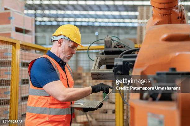 technical engineer using computer workstation, expertly programming commands for robotic arm. testament to the fusion of technology, innovation, and expertise in modern industrial settings. wearing protective workwear, gazes intently at the computer. - pallet truck stock pictures, royalty-free photos & images