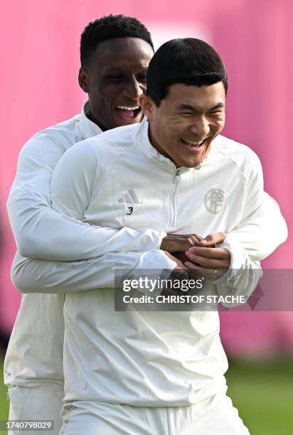 Bayern Munich's French defender Bouna Sarr jokes with Bayern Munich's South Korean defender Kim Min-Jae at the beginning of a training session at the...