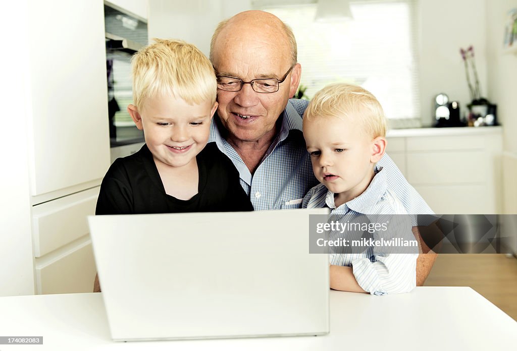 Grandfather and two grandsons look at laptop together