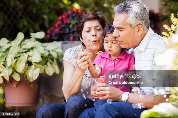 grandparents and granddaughter making bubbles - grandfather stock pictures, royalty-free photos & images