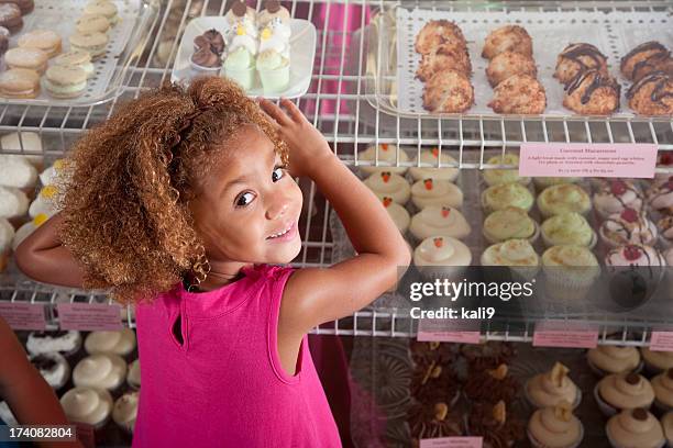 niña en tienda de magdalena con glaseado - cupcakes girls fotografías e imágenes de stock