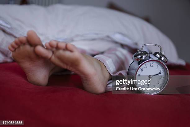 In this photo illustration Dirty feet in a bed and a clock on October 04, 2023 in Bonn, Germany.