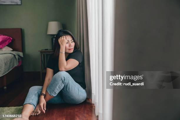 sad and depressed woman sitting alone at home on the floor - povo do sudeste asiático imagens e fotografias de stock