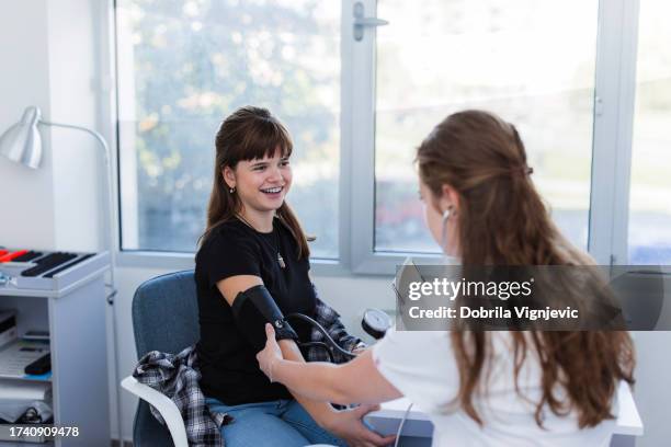 teenage girl having her blood pressure measured - happiness meter stock pictures, royalty-free photos & images