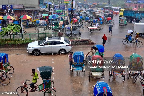 Vehicles ride along a street as it rains in Dhaka on October 23, 2023.