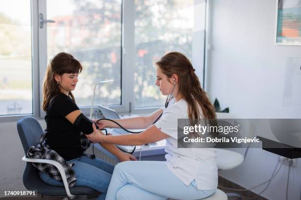 teenage girl having her blood pressure measured - hypertensive stock pictures, royalty-free photos & images