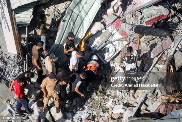 Palestinian emergency services and local citizens search for victims in buildings destroyed during Israeli air raids in the southern Gaza Strip on...