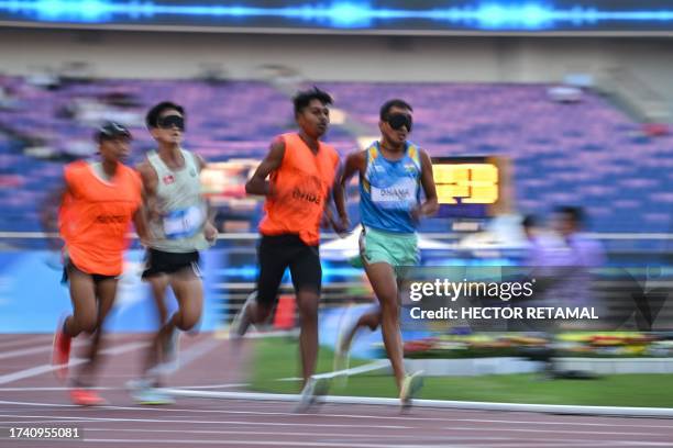 India's Ankur Dhama accompanied by his guide competes in the men's 5000m-T11 final at the Huanglong Sport Centre Stadium during the 2022 Asian Para...