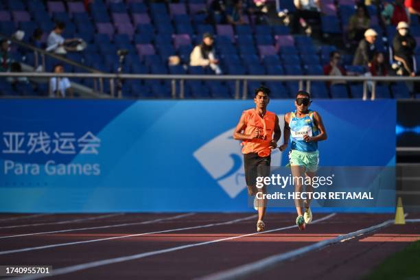 India's Ankur Dhama accompanied by his guide competes in the men's 5000m-T11 final at the Huanglong Sport Centre Stadium during the 2022 Asian Para...