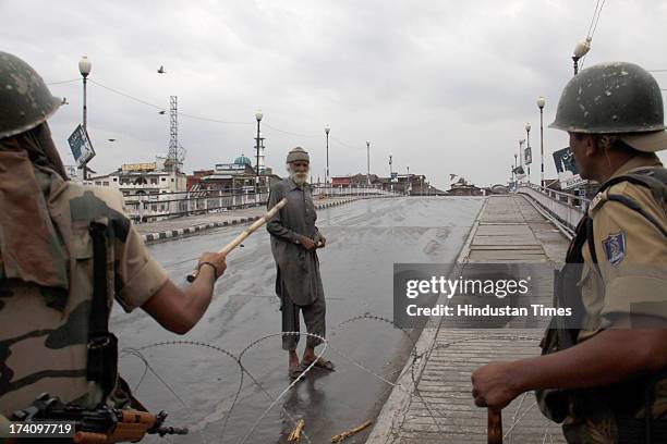 Paramilitary soldier stop Kashmiri Muslim man during second day of curfew on July 20, 2013 in Srinagar, India. Curfew remained in force for the...