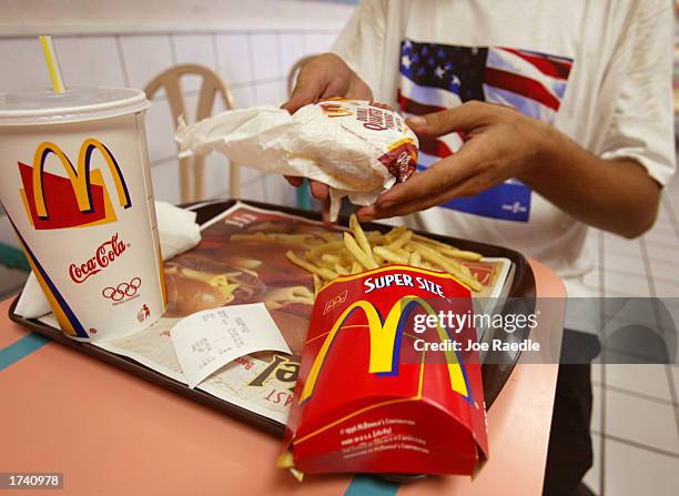 Jeff Baughman unwraps his double quarterpounder with cheese, a super fries and a super coke at a McDonald's restaurant July 18, 2002 in Miami Beach,...