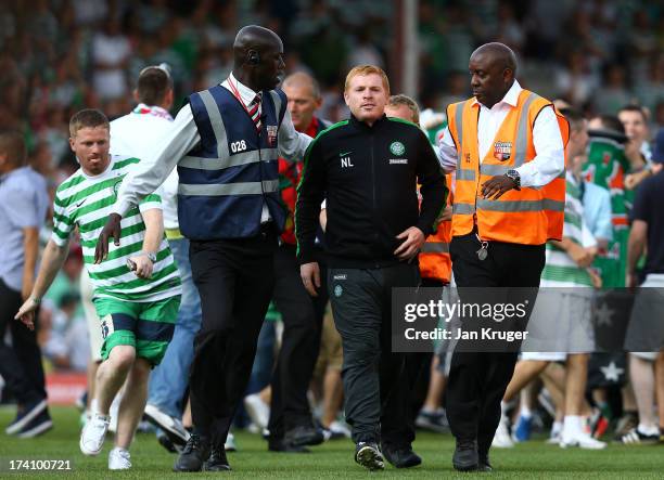 Manager of Celtic Neil Lennon is escorted off the pitch as traveling fans invade the pitch during a pre season friendly match between Brentford and...