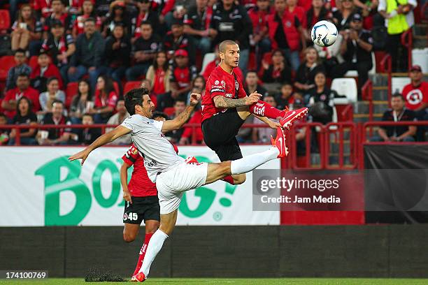 Dario Benedetto of Tijuana struggles for the ball with Facundo Erpen of Atlas during the Apertura 2013 Liga Bancomer MX at Caliente Stadium on july...