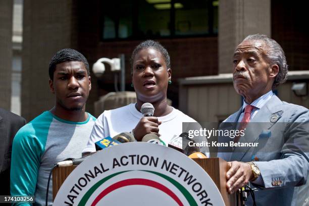 Trayvon Martin's mother Sybrina Fulton speaks at a podium as Trayvon Martin's brother Jahvaris Fulton and Rev. Al Sharpton attend a rally honoring...