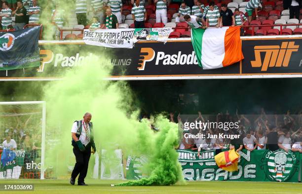 Safety officer removes a smoke bomb from the pitch during a pre season friendly match between Brentford and Celtic at Griffin Park on July 20, 2013...