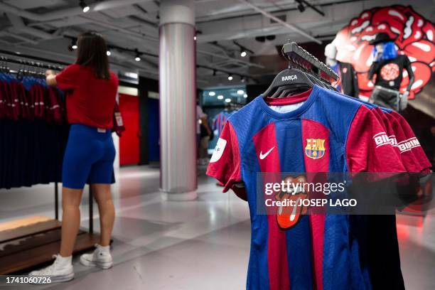 This picture taken on October 23, 2023 at the FC Barcelona store, in Barcelona, shows the club's new jersey featuring the famous logo of the Rolling...